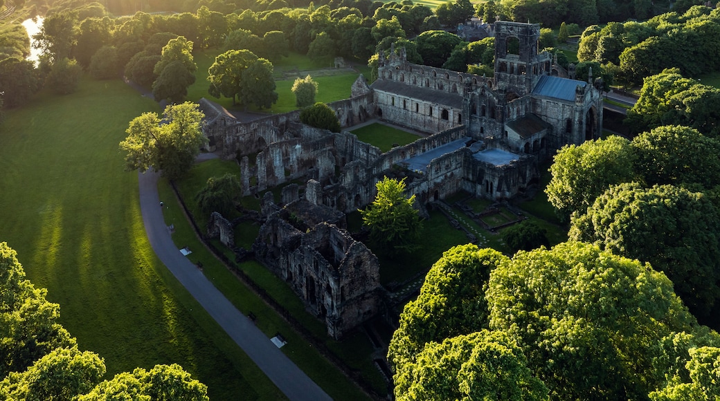 Une vue aérienne d’un château historique, entouré d’une végétation luxuriante et d’une pelouse bien entretenue.