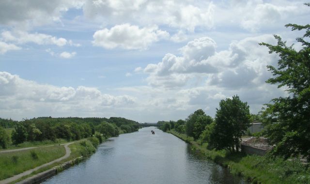 A river with a narrow path on one side and trees on the other.