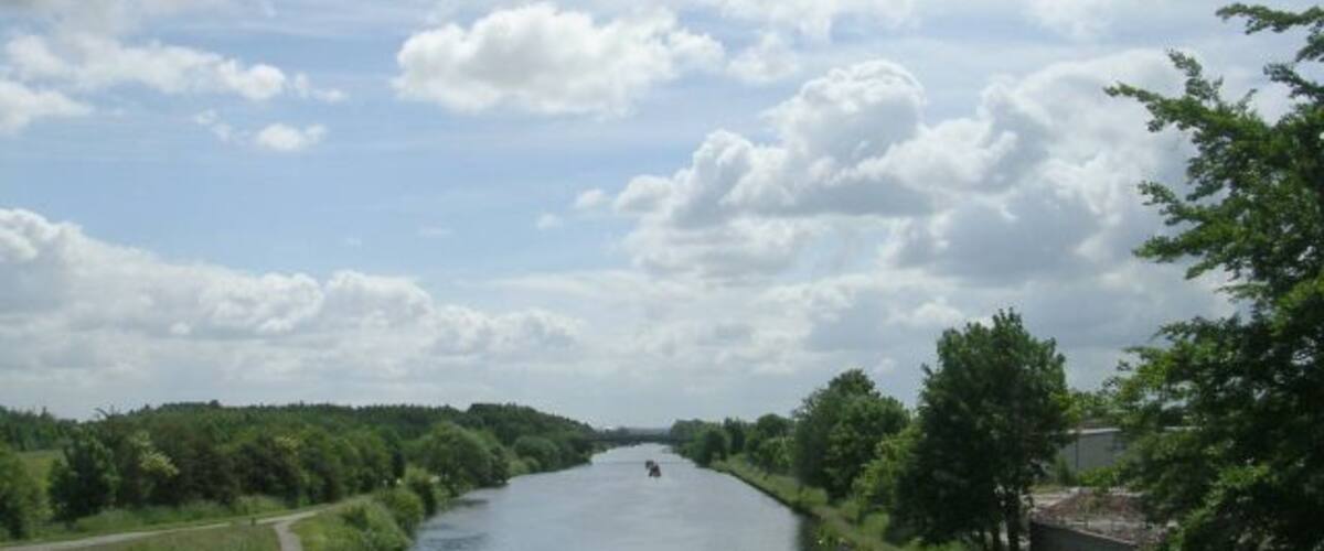 A river with a narrow path on one side and trees on the other.