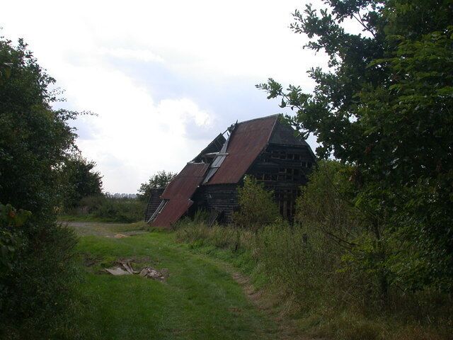 A tilted barn in a rural setting with a path leading to it.