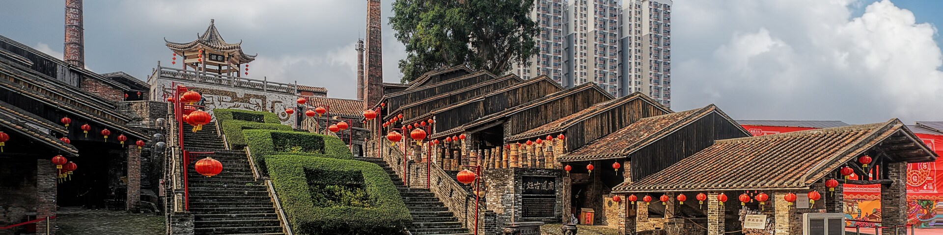 Um pátio tradicional chinês com degraus de pedra, lanternas vermelhas e uma pagoda.