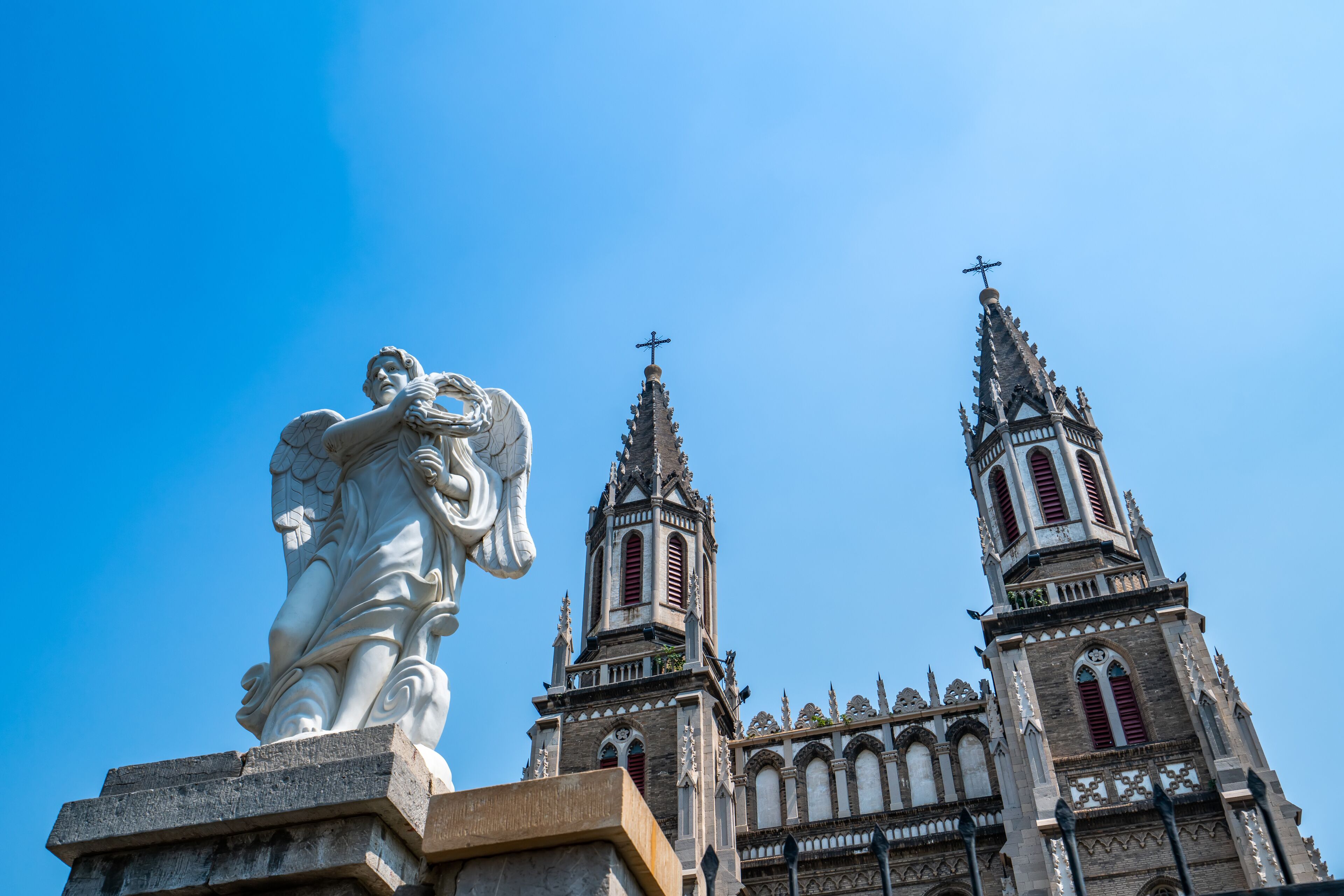 A cathedral with two towers and a large angel statue.