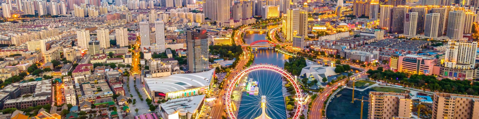 A cityscape with a prominent Ferris wheel, a river, and dense urban architecture.
