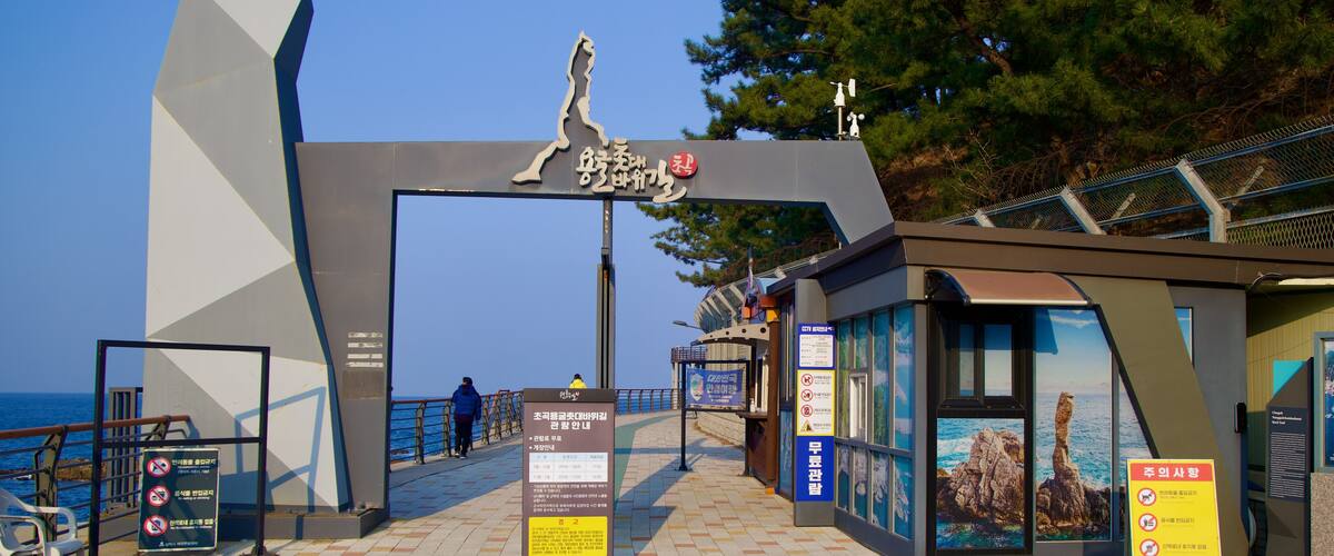 A coastal walkway with a large archway, informational signs, and a view of the sea.