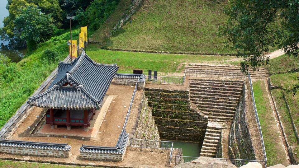 A traditional Korean temple with a tiled roof, a stone courtyard, and a small pond.
