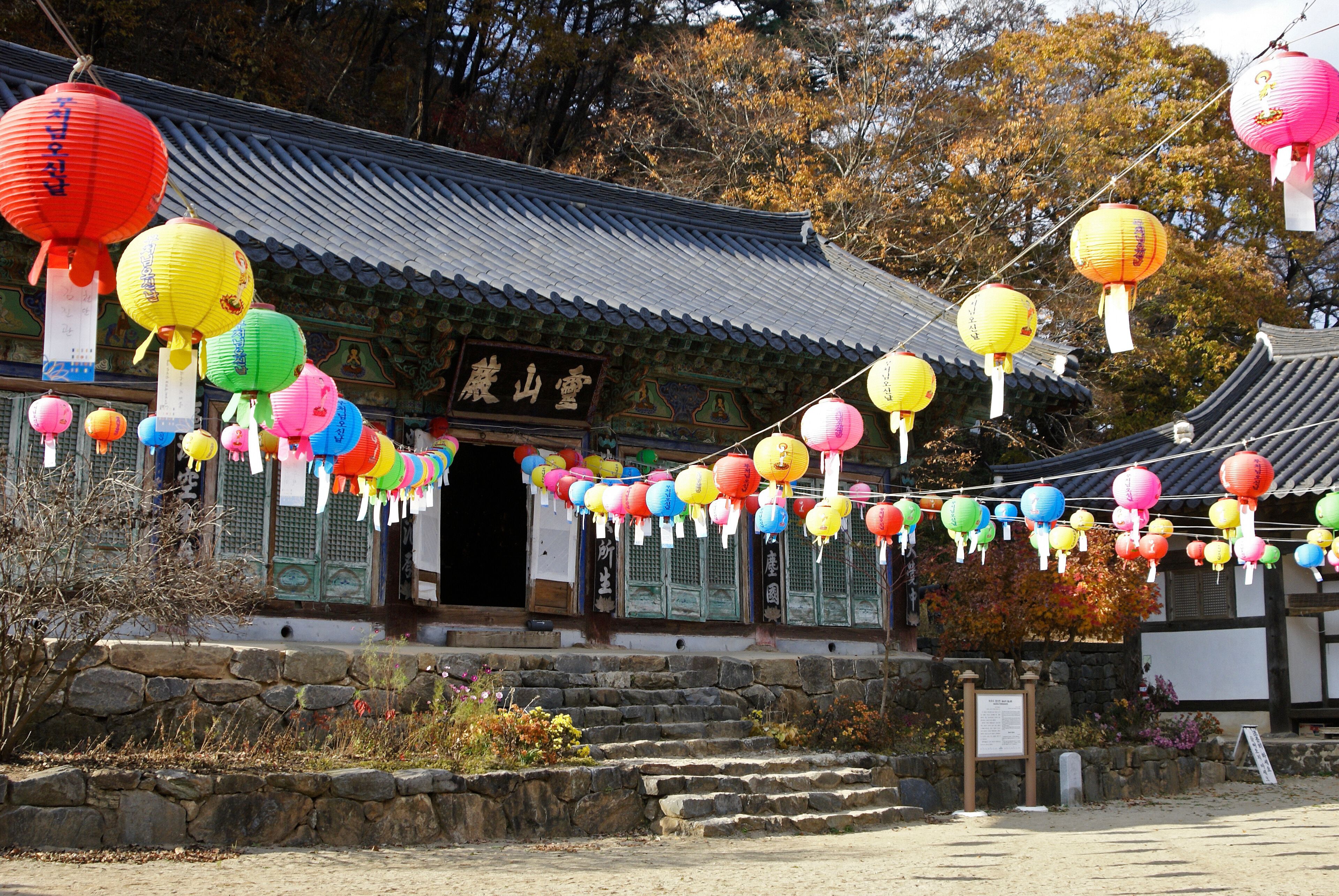 Colorful paper lanterns frame a small shrine in autumn at Magoksa Buddhist temple, Gongju, South Korea.