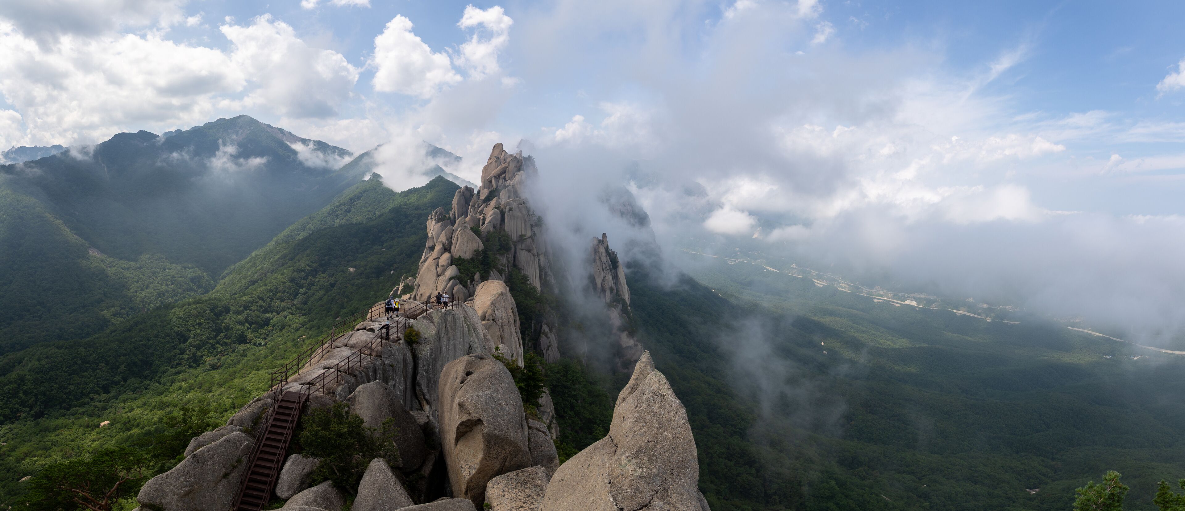 A mountain landscape with a prominent rock formation and a staircase leading up to it.