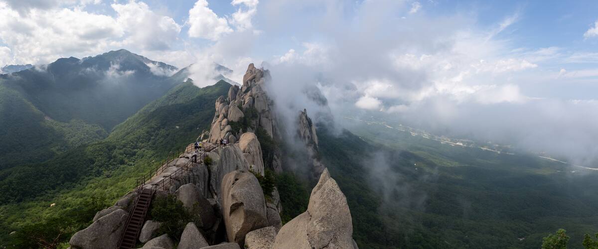 A mountain landscape with a prominent rock formation and a staircase leading up to it.