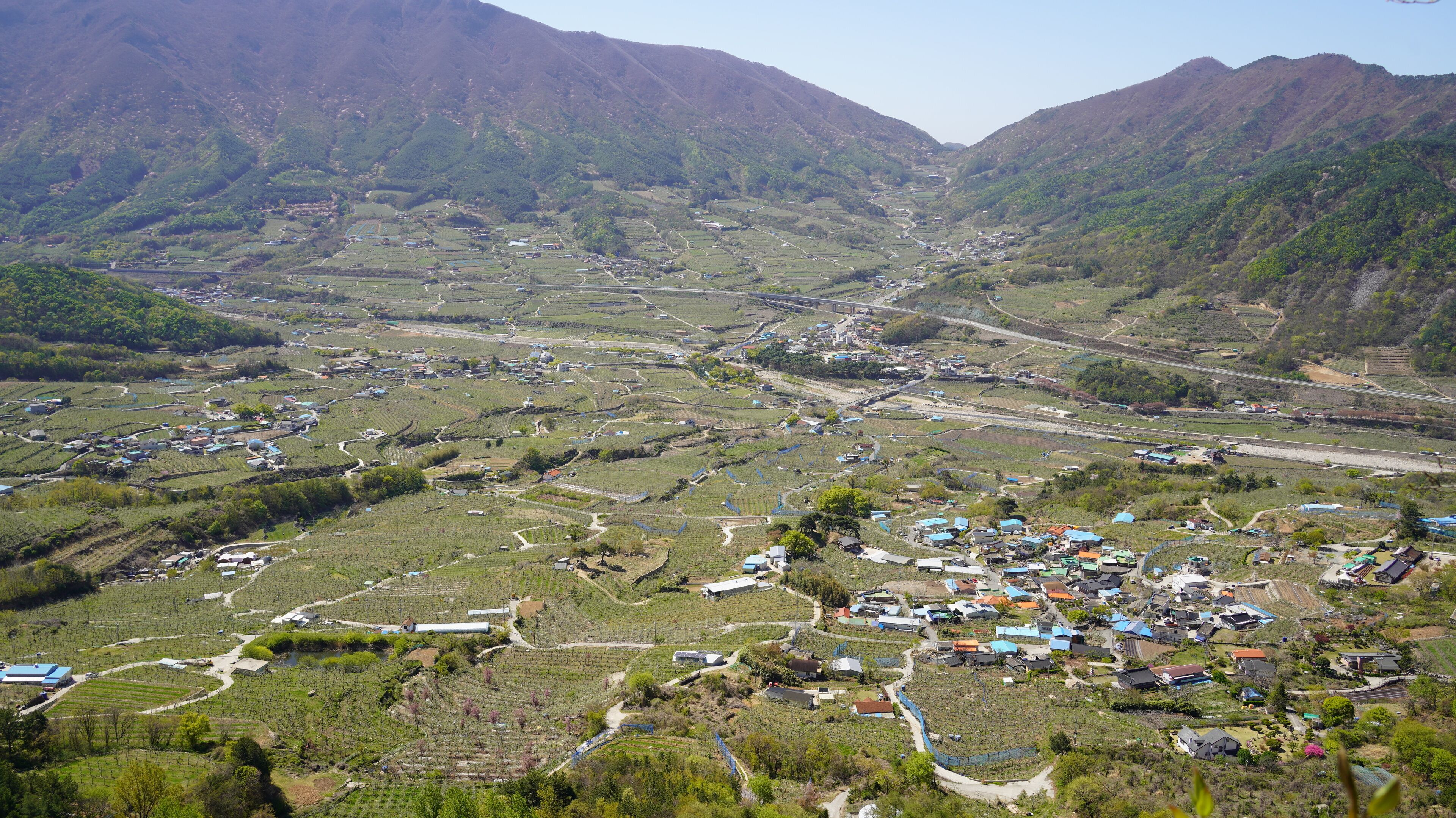 A mountainous landscape with terraced fields and scattered buildings.