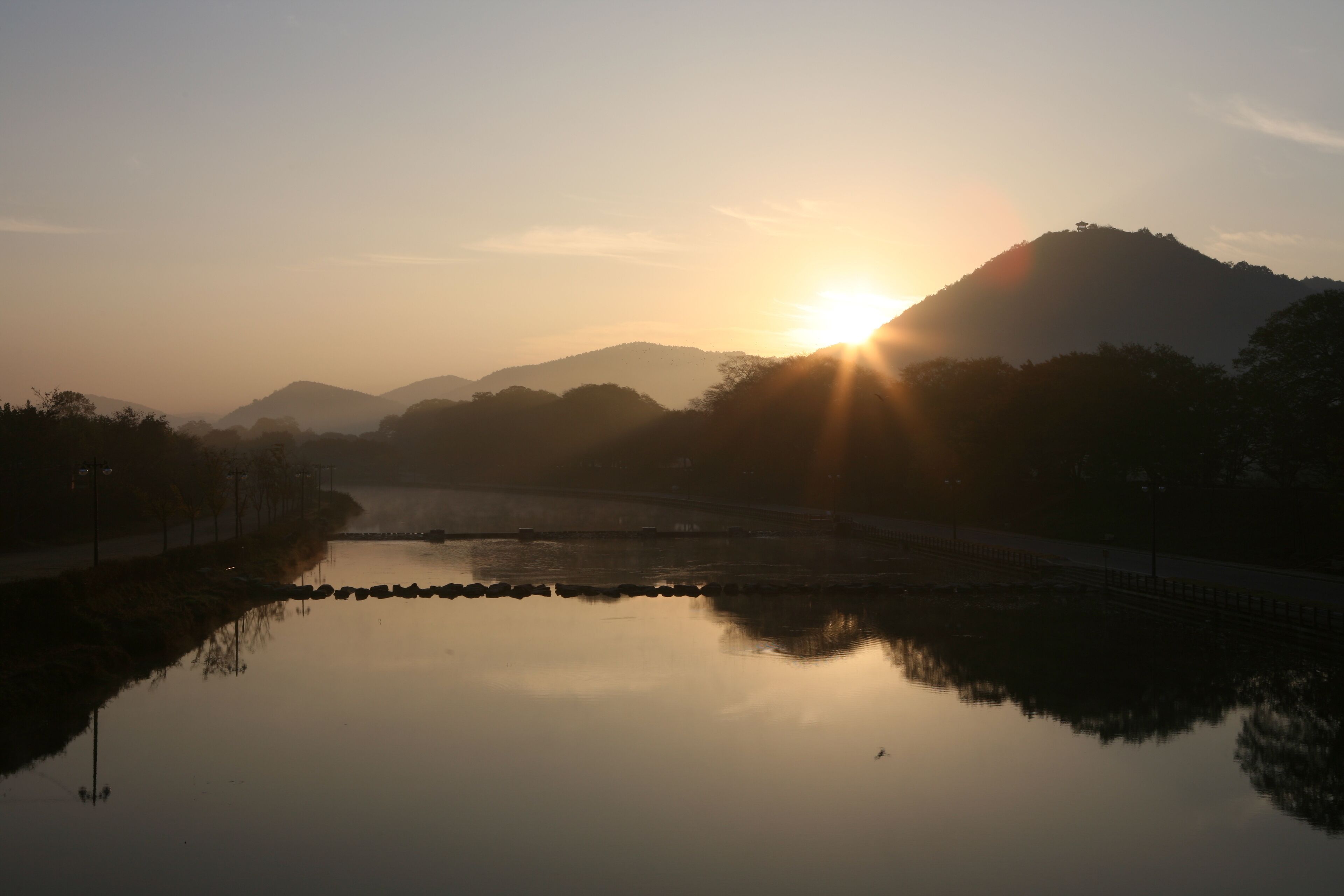 A sunrise over a calm lake with a mountain in the background.