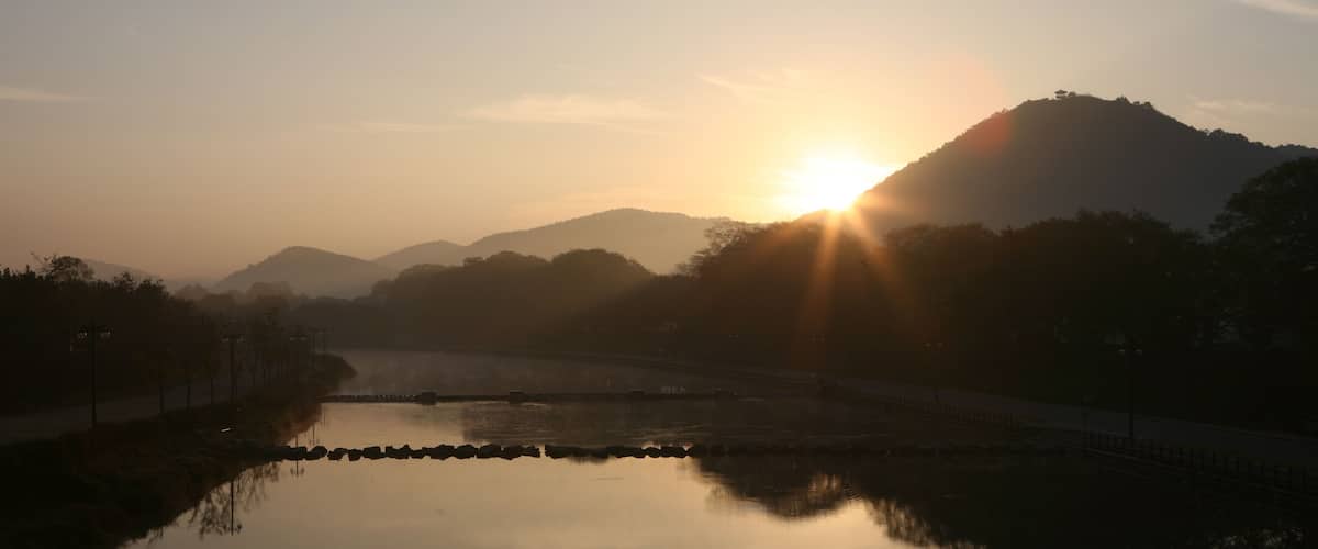 A sunrise over a calm lake with a mountain in the background.
