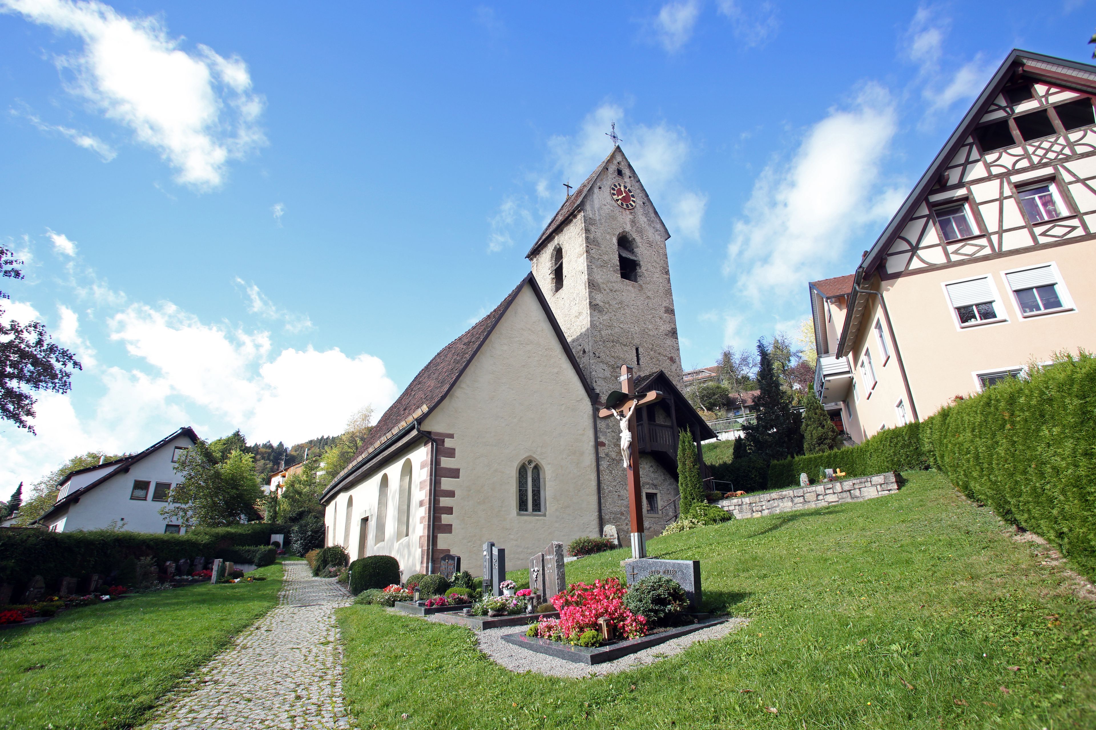 A church with a clock tower, surrounded by houses and a cobblestone path.