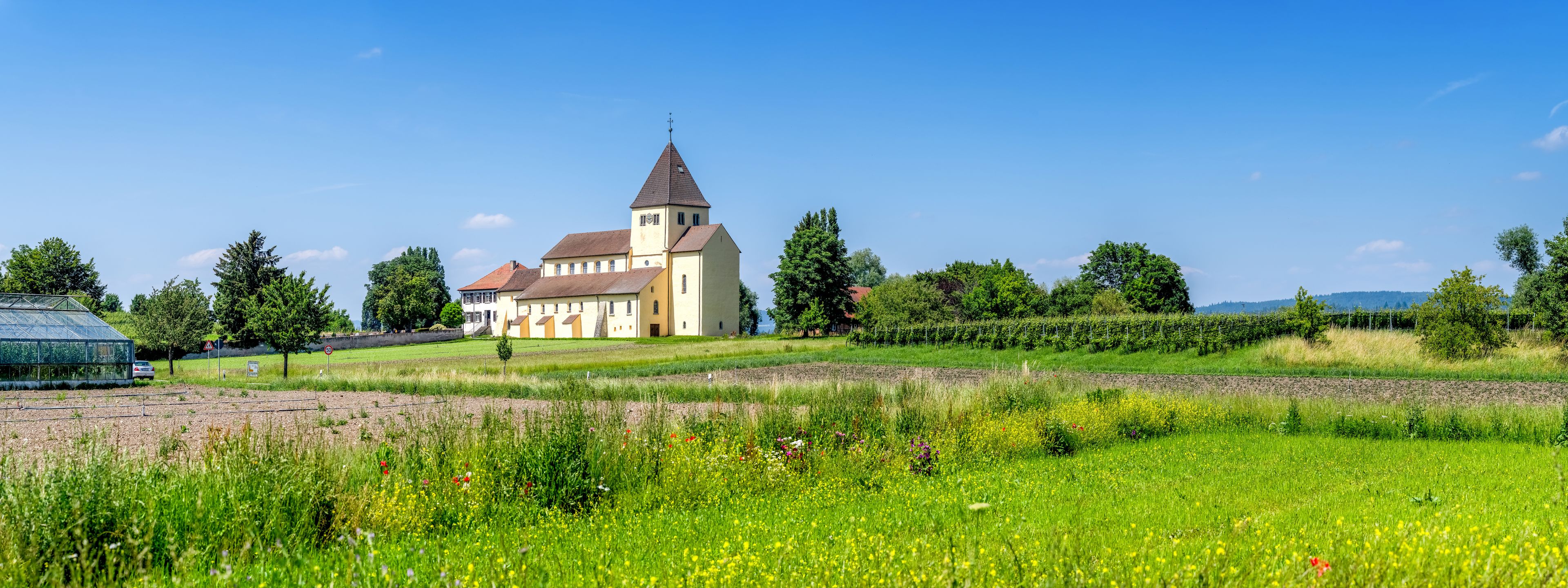 A church with a bell tower, surrounded by fields and trees.