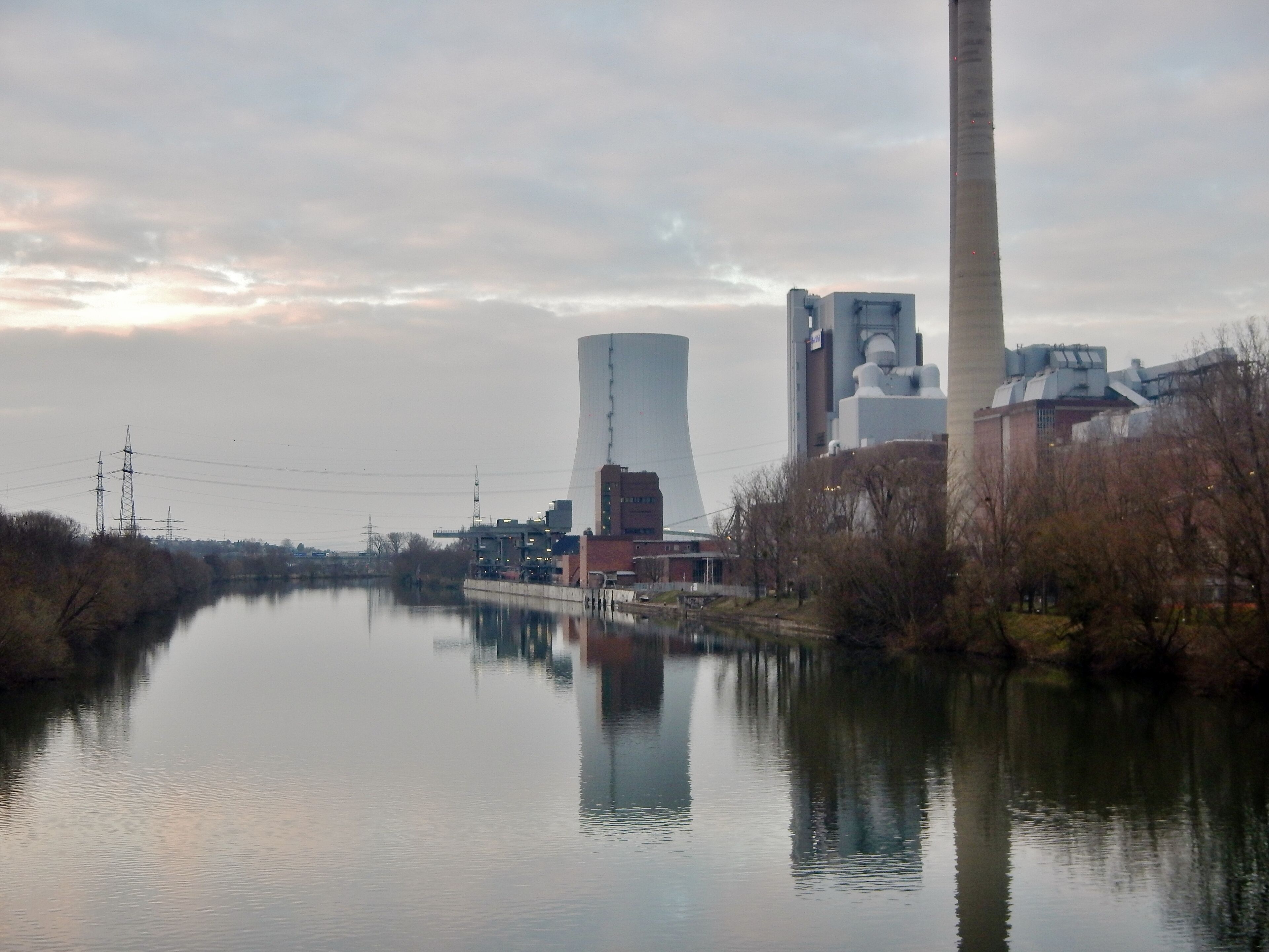 A river with industrial buildings and a cooling tower.