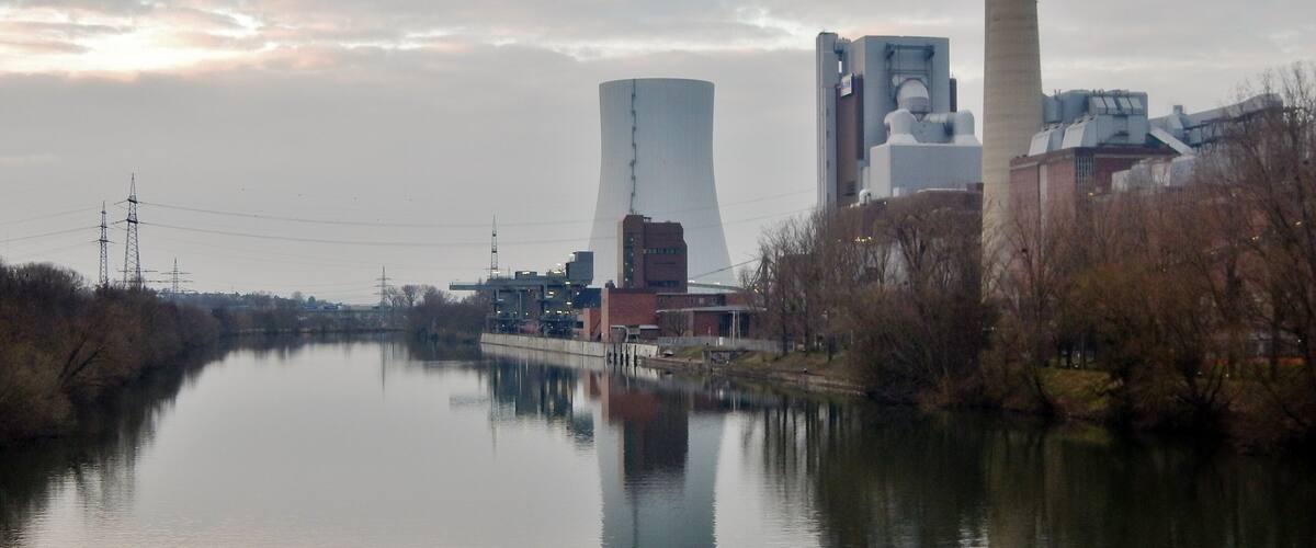 A river with industrial buildings and a cooling tower.