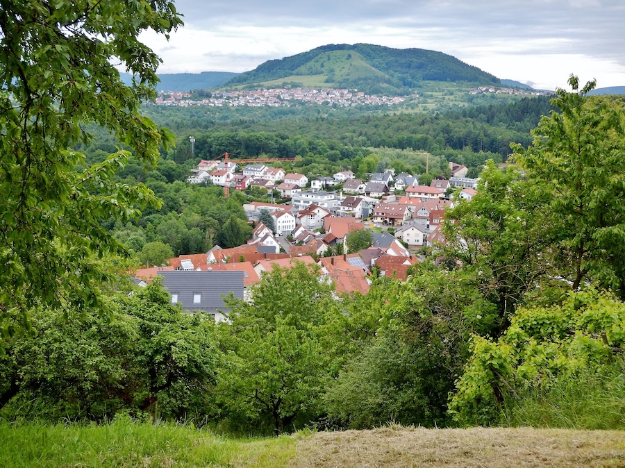 A town nestled in a valley with a backdrop of rolling hills and a mountain.