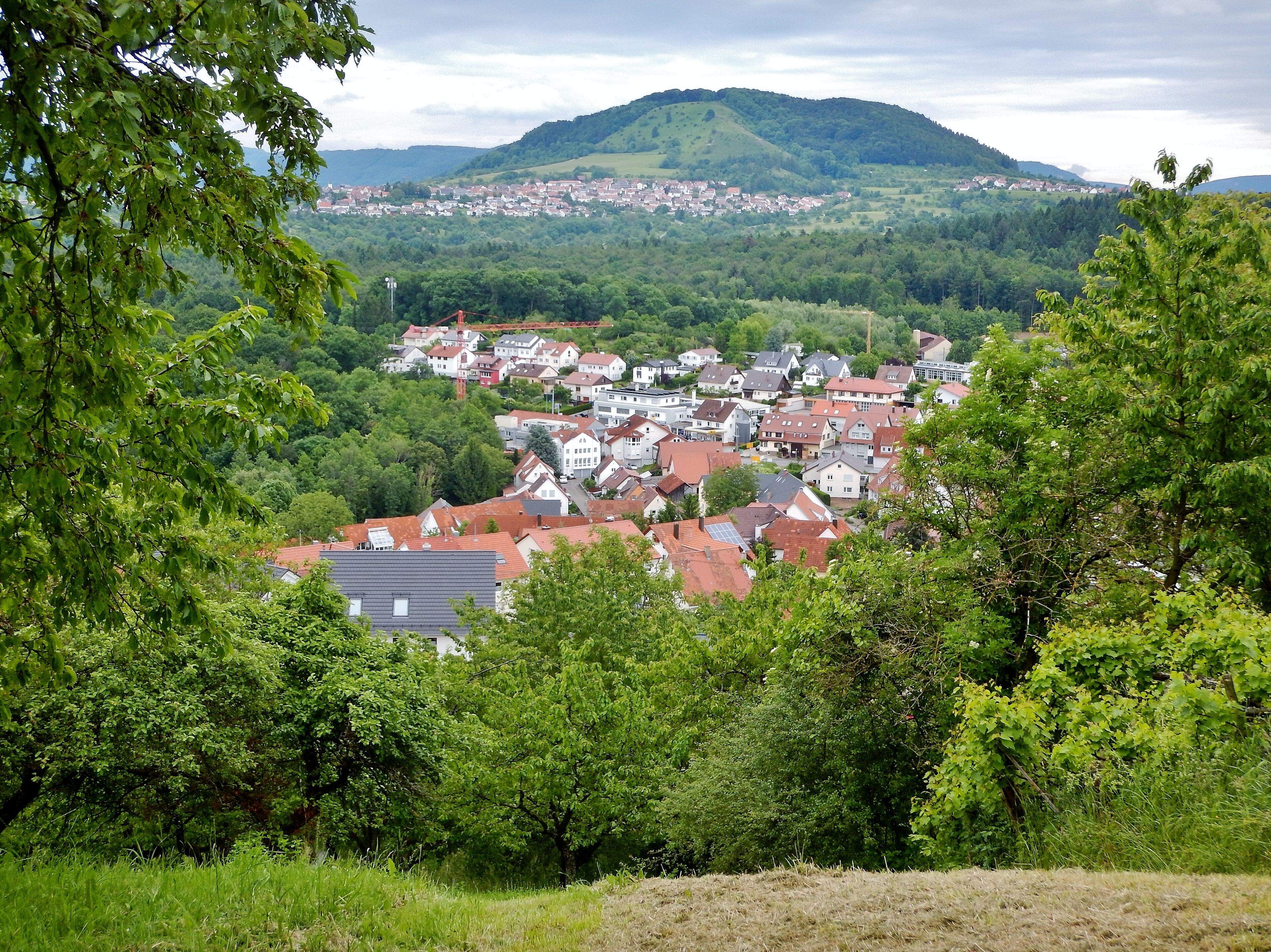 A town nestled in a valley with a backdrop of rolling hills and a mountain.