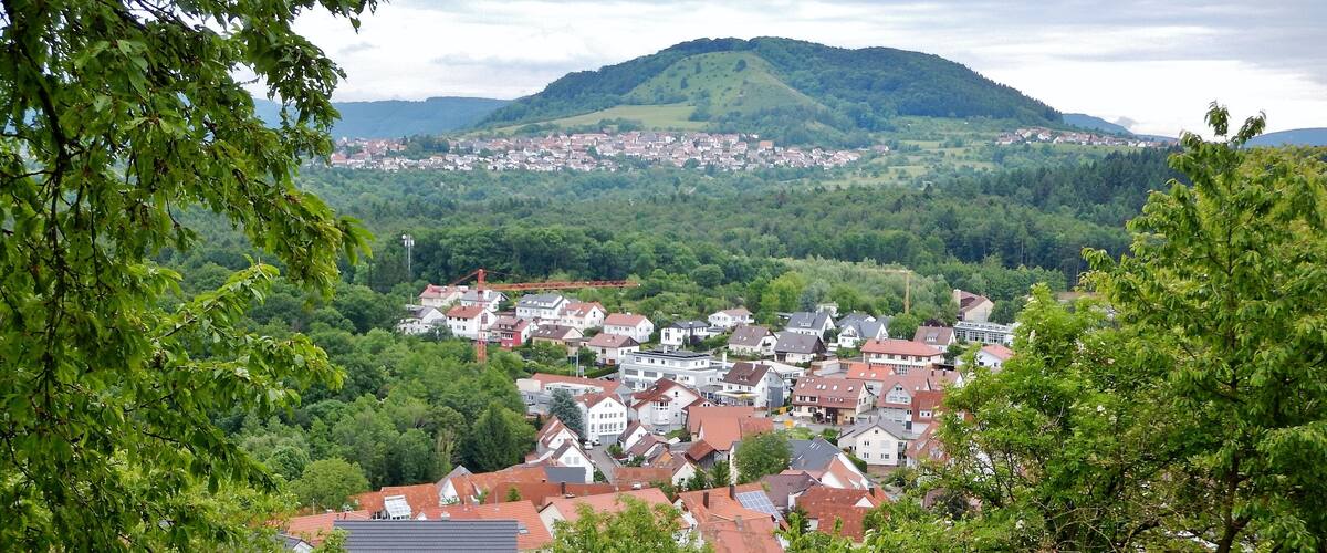 A town nestled in a valley with a backdrop of rolling hills and a mountain.