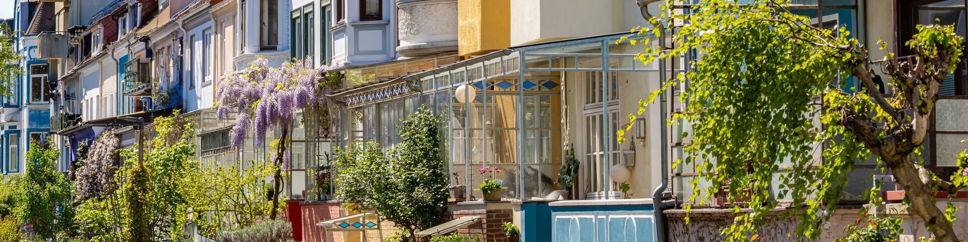 A row of colorful townhouses with a glass conservatory and lush greenery.