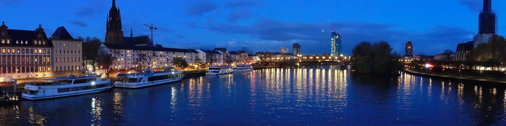 A river with boats, historic buildings, and a clock tower.