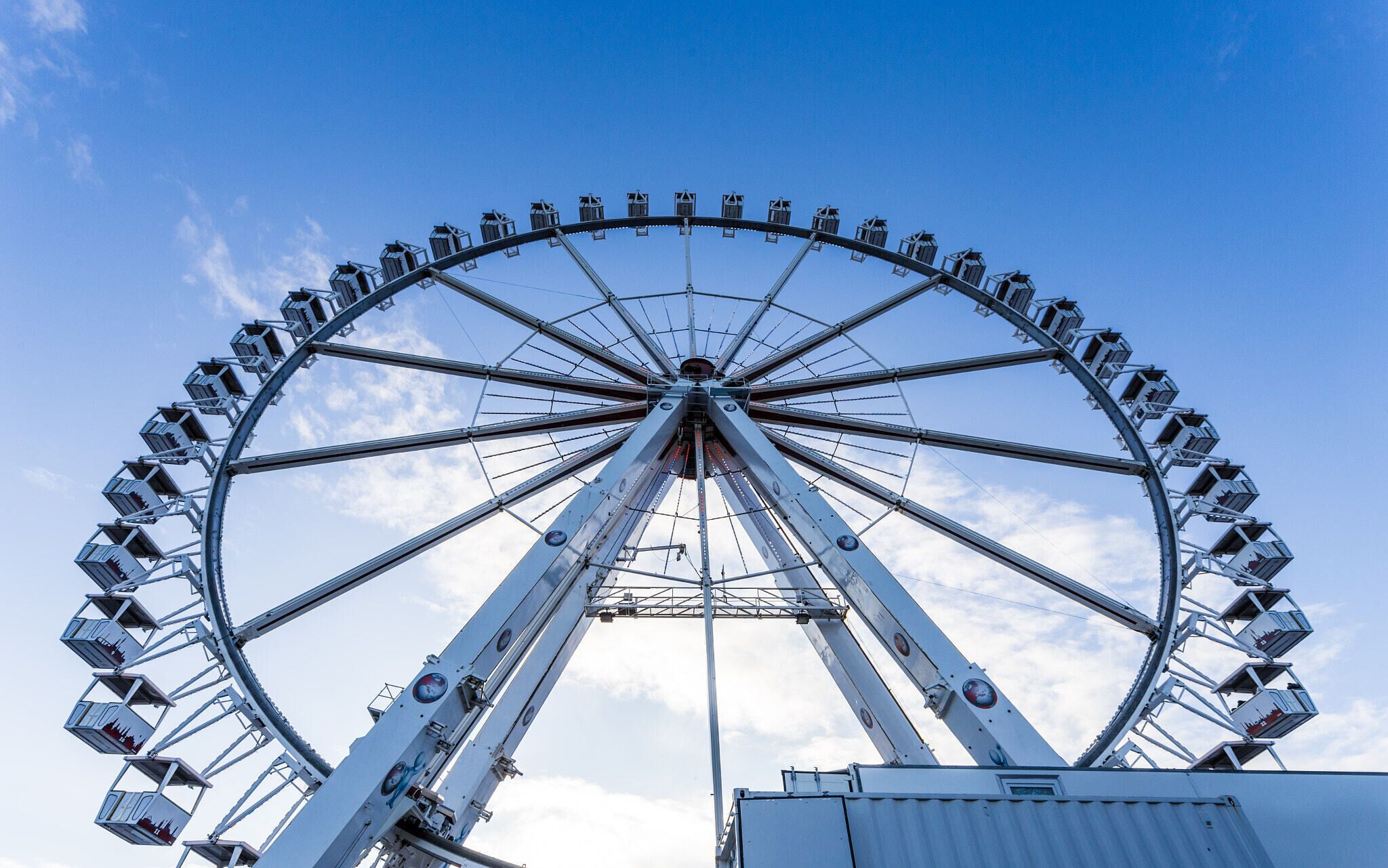 A large Ferris wheel with multiple cabins against a clear blue sky.