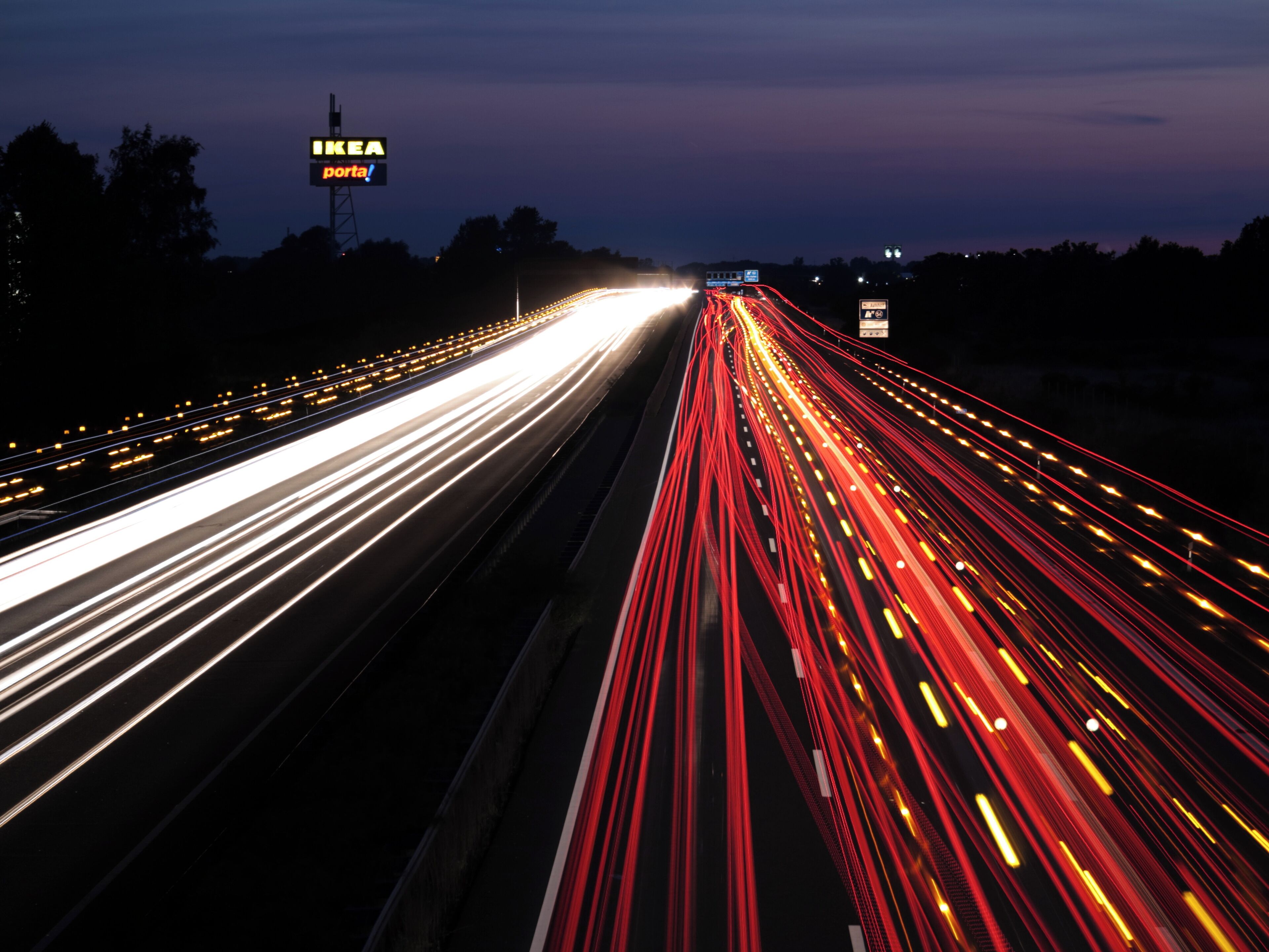 A highway at dusk with light trails from vehicles.