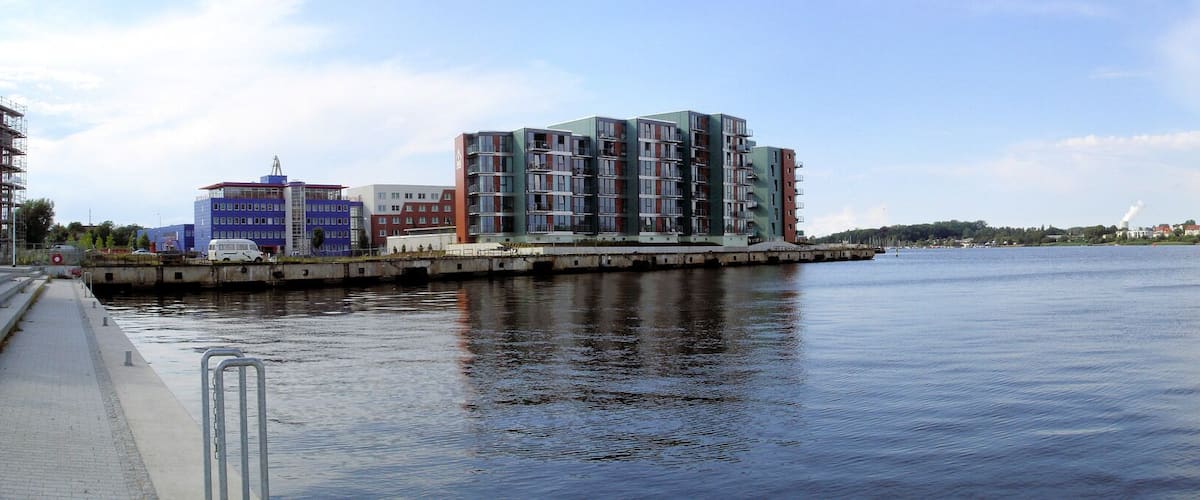 A river with a bridge, modern buildings, and a distant city skyline.
