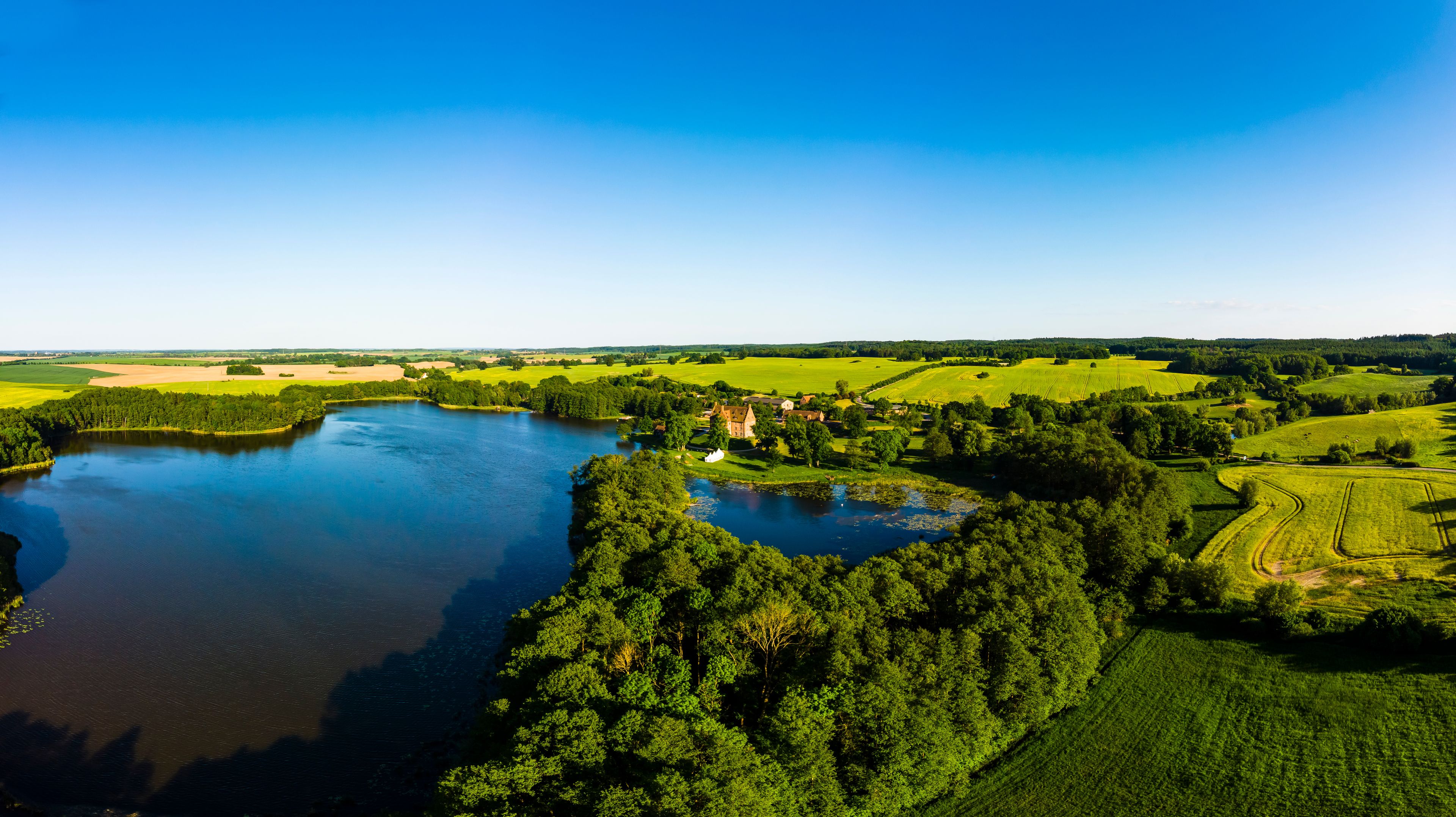 A river winding through a lush landscape with a castle-like structure near the water's edge.