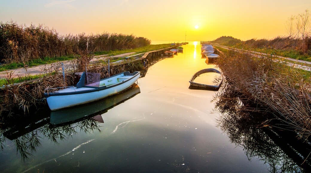 Une rivière paisible au coucher du soleil, avec des bateaux amarrés le long des rives.