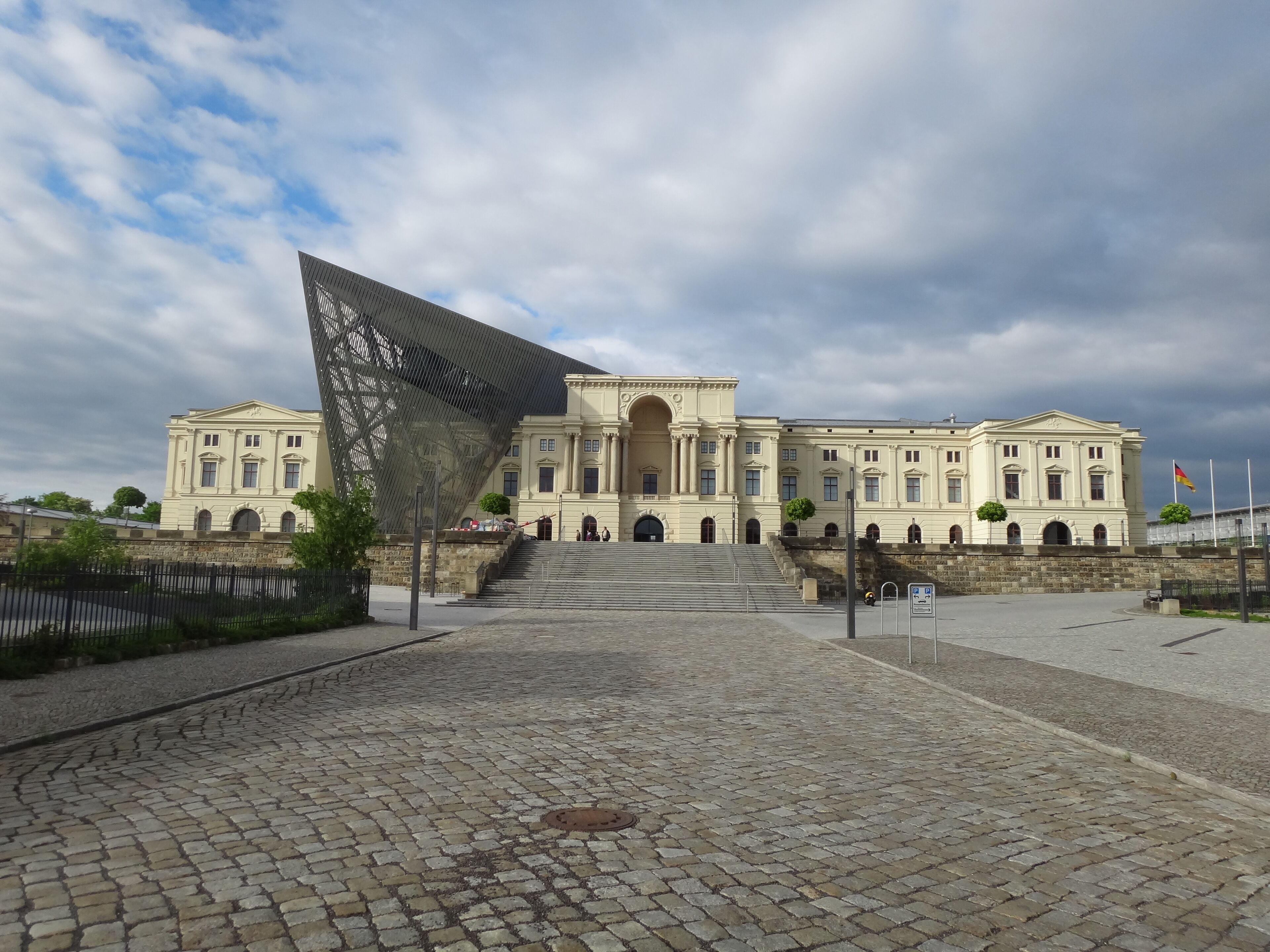 A large classical building with a central archway and steps leading up to it.