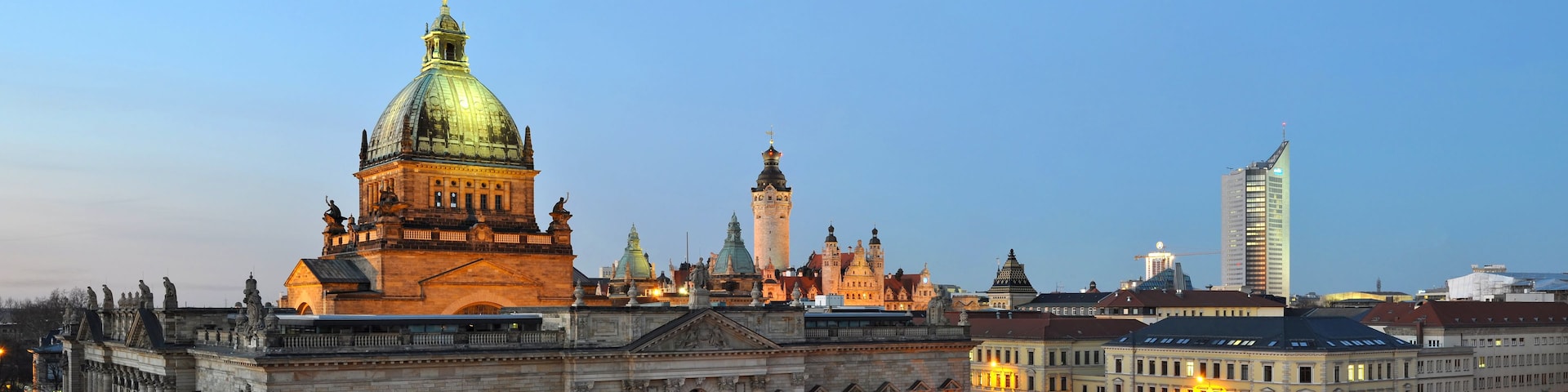Ein historisches Gebäude mit einer großen Kuppel und einem Turm, umgeben von modernen Bauten.