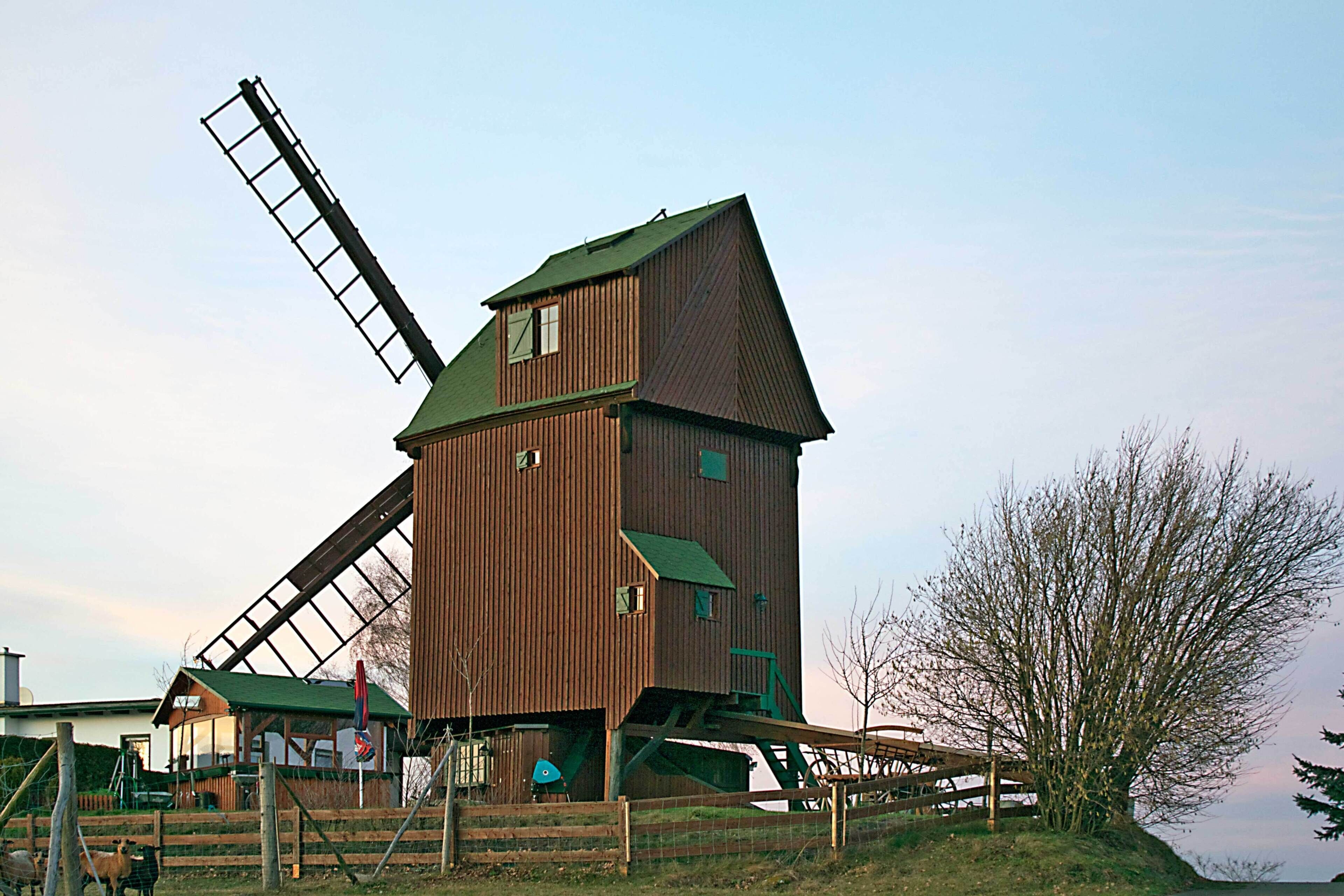 A windmill with a wooden structure and a metal windlass.