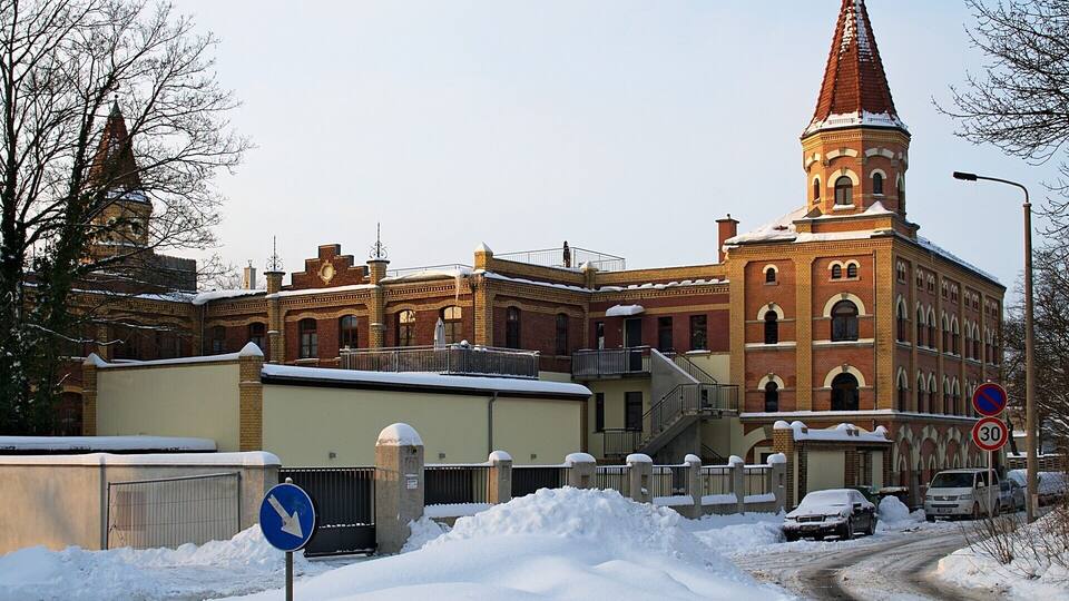 Ein historisches Gebäude mit einem hohen Turm und einer verschneiten Straße.