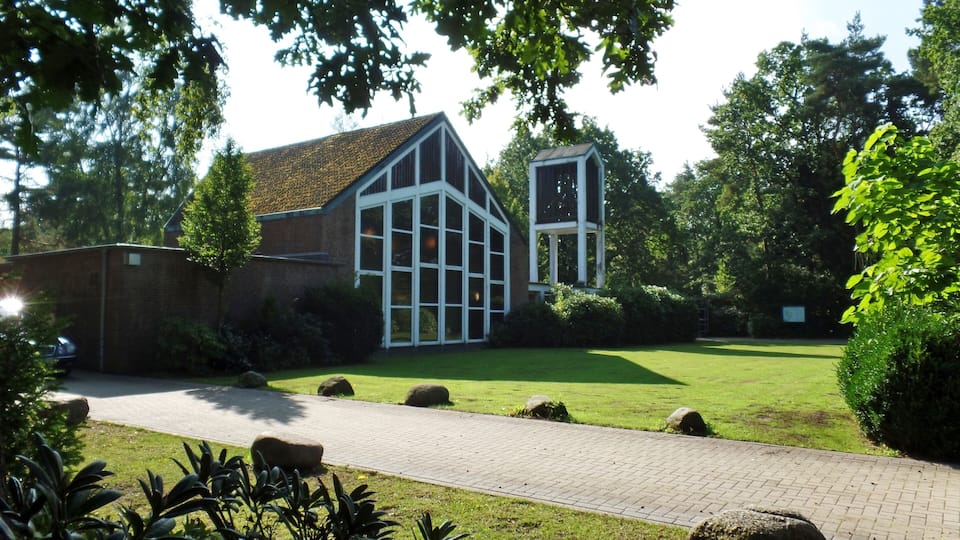 A modern building with large windows and a brick facade, surrounded by a well-maintained lawn and a paved pathway.