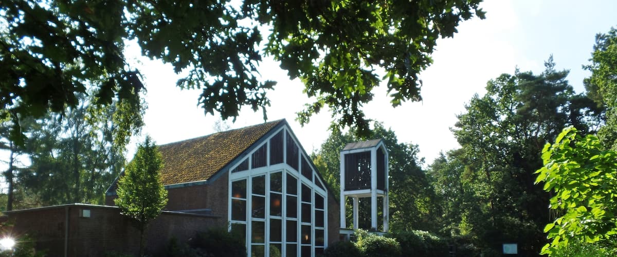 A modern building with large windows and a brick facade, surrounded by a well-maintained lawn and a paved pathway.