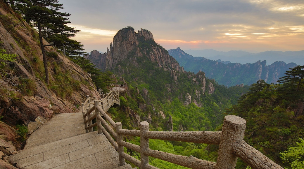 A stone staircase with wooden railings leading up a mountainous terrain.