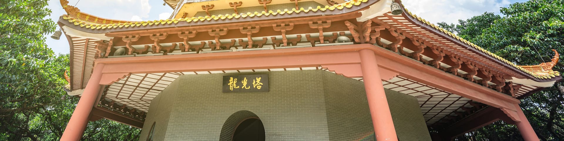 A multi-tiered pagoda with traditional architecture, a clear sky, and lush greenery.