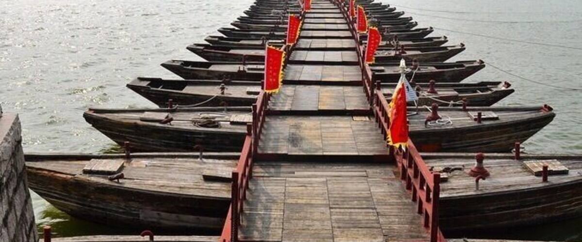 Un muelle de madera con una puerta tradicional china al fondo.