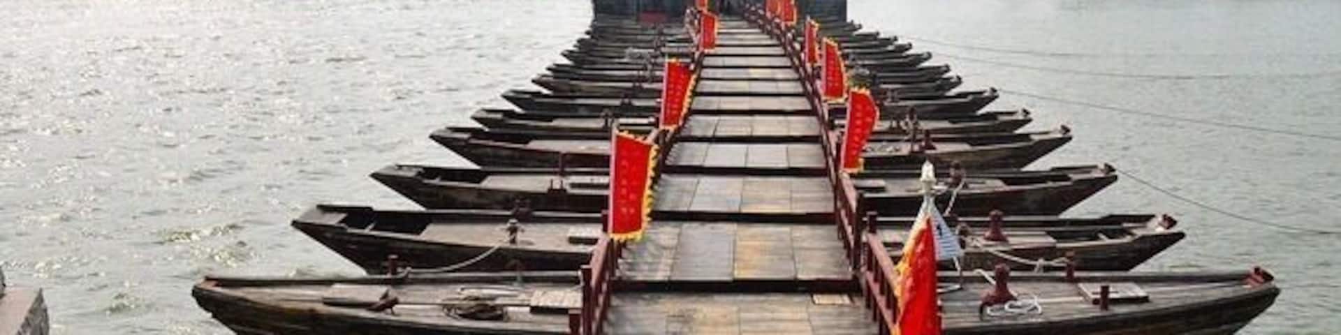 A wooden boat dock with a traditional Chinese gate in the background.