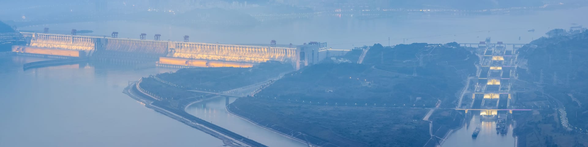 A large dam with multiple gates, a river, and a bridge.