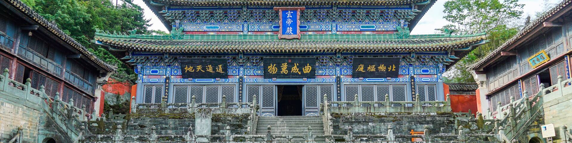 A traditional Chinese building with ornate blue and gold decorations, a large staircase leading to the entrance, and a stone lantern in the foreground.