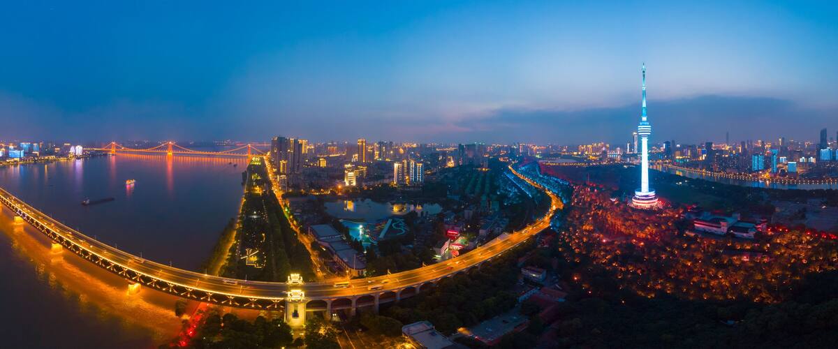 A cityscape at night with a prominent bridge, a tall tower, and a river reflecting city lights.