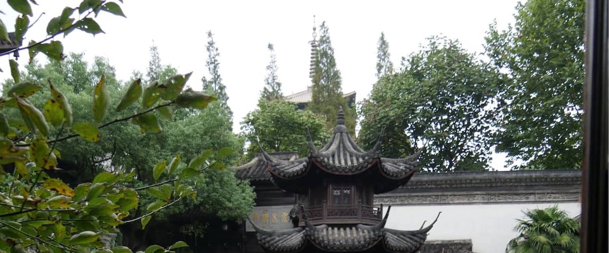 A traditional Chinese pavilion over a pond with koi fish, surrounded by lush greenery.