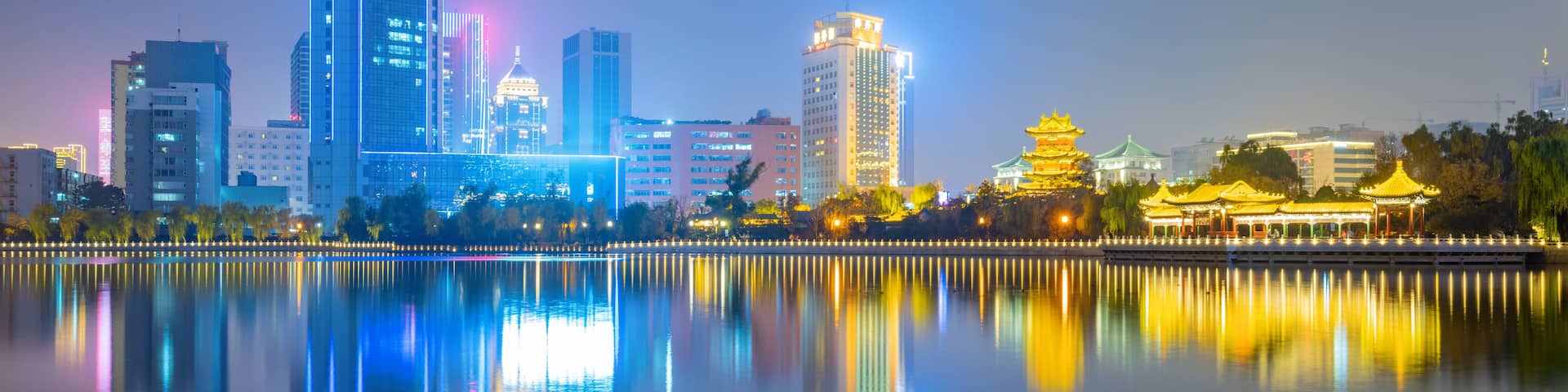 A city skyline at night with reflections in a calm body of water.