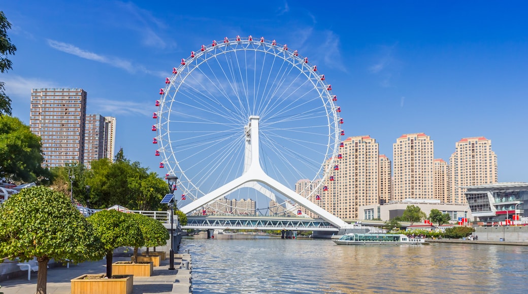 A Ferris wheel, a river, and modern buildings.