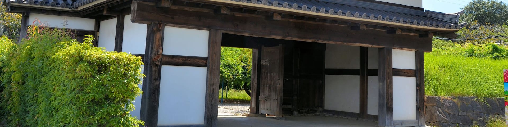 A traditional Japanese building with a curved roof, wooden beams, and a stone pathway leading to the entrance.
