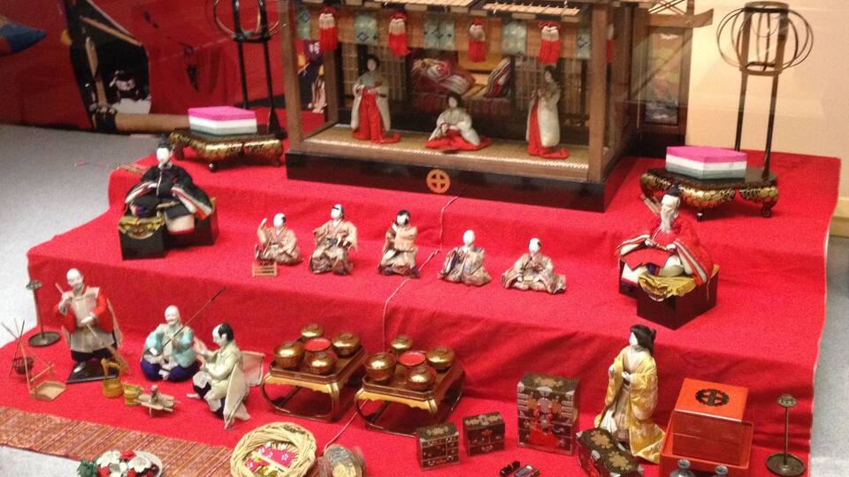 Eine traditionelle japanische Präsentation mit Miniaturfiguren, einer hölzernen Bühne und verschiedenen kulturellen Artefakten.