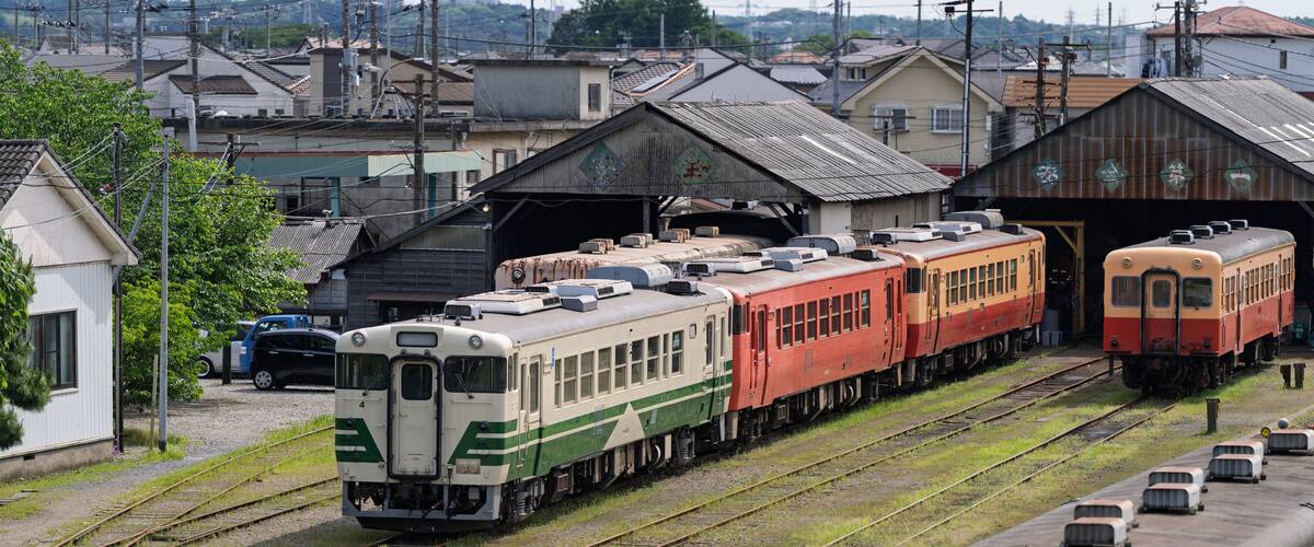 A train yard with multiple trains parked on tracks, surrounded by buildings and power lines.