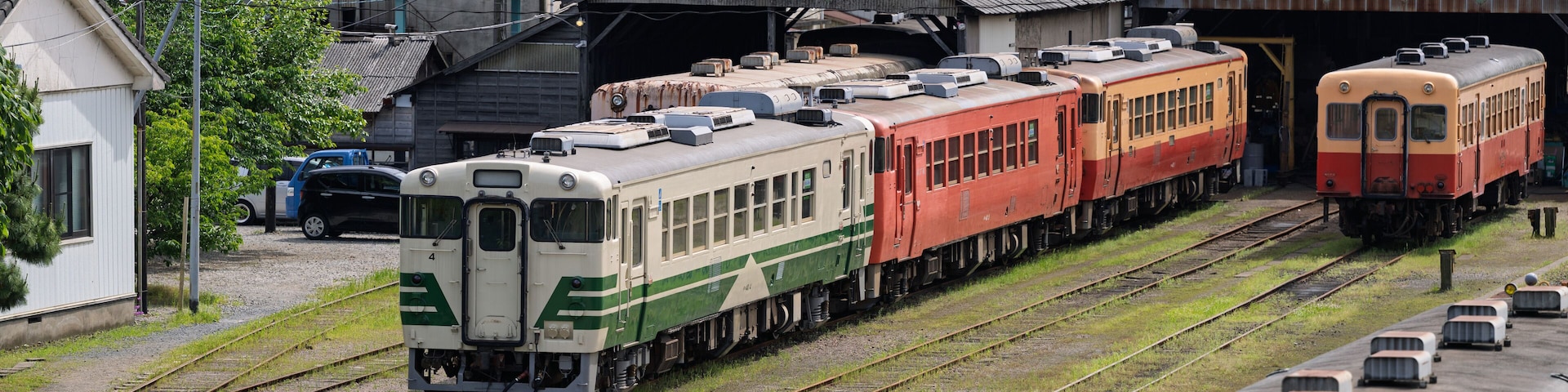 A train yard with multiple trains parked on tracks, surrounded by buildings and power lines.
