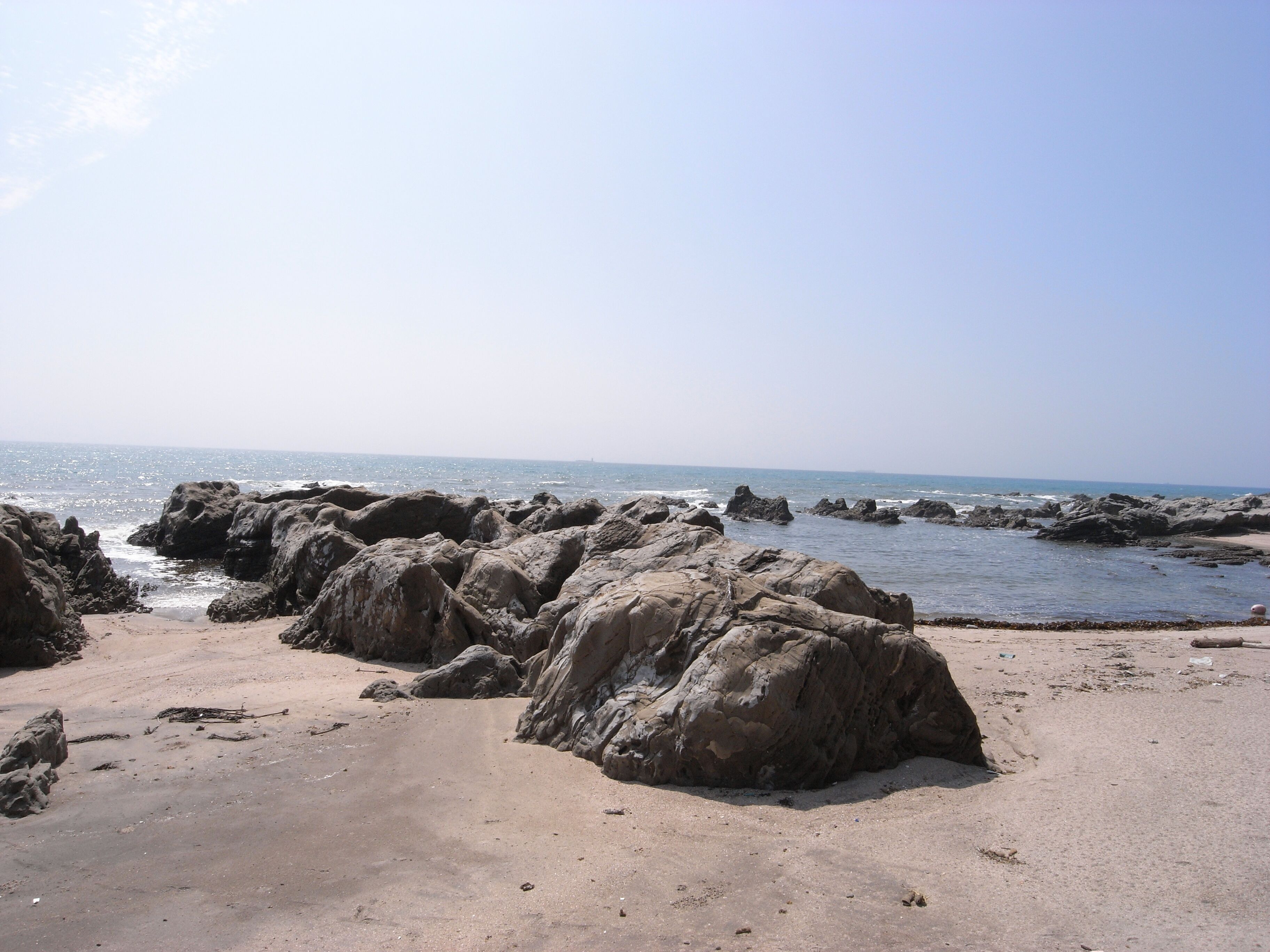 A rocky beach with large boulders and calm sea.